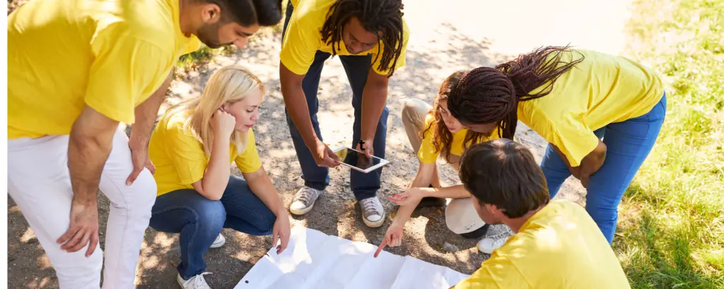 A group of people huddled around a map, working together to solve a scavenger hunt.